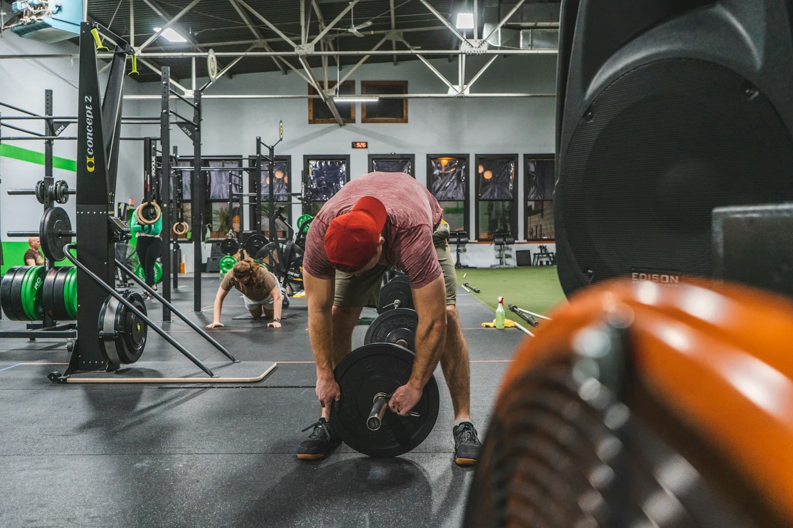 Person loading weight plates onto a barbell in a busy gym