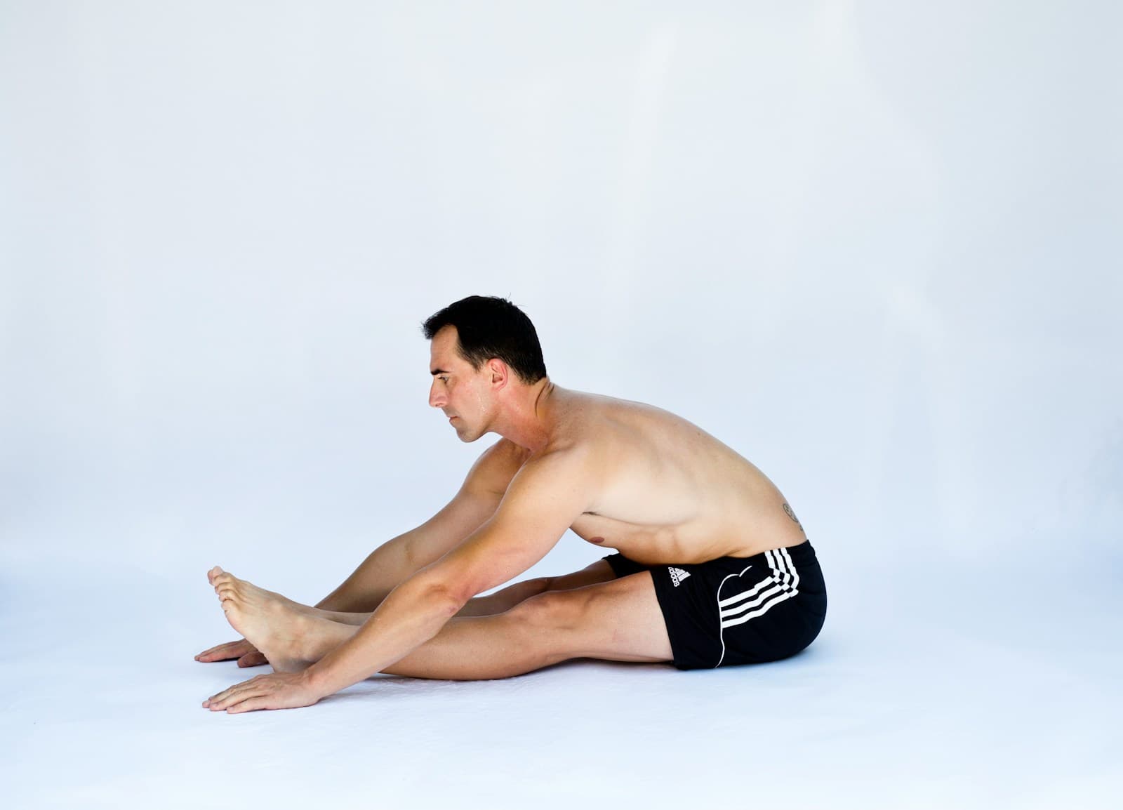 Man performing a seated forward fold hamstring stretch with straight legs