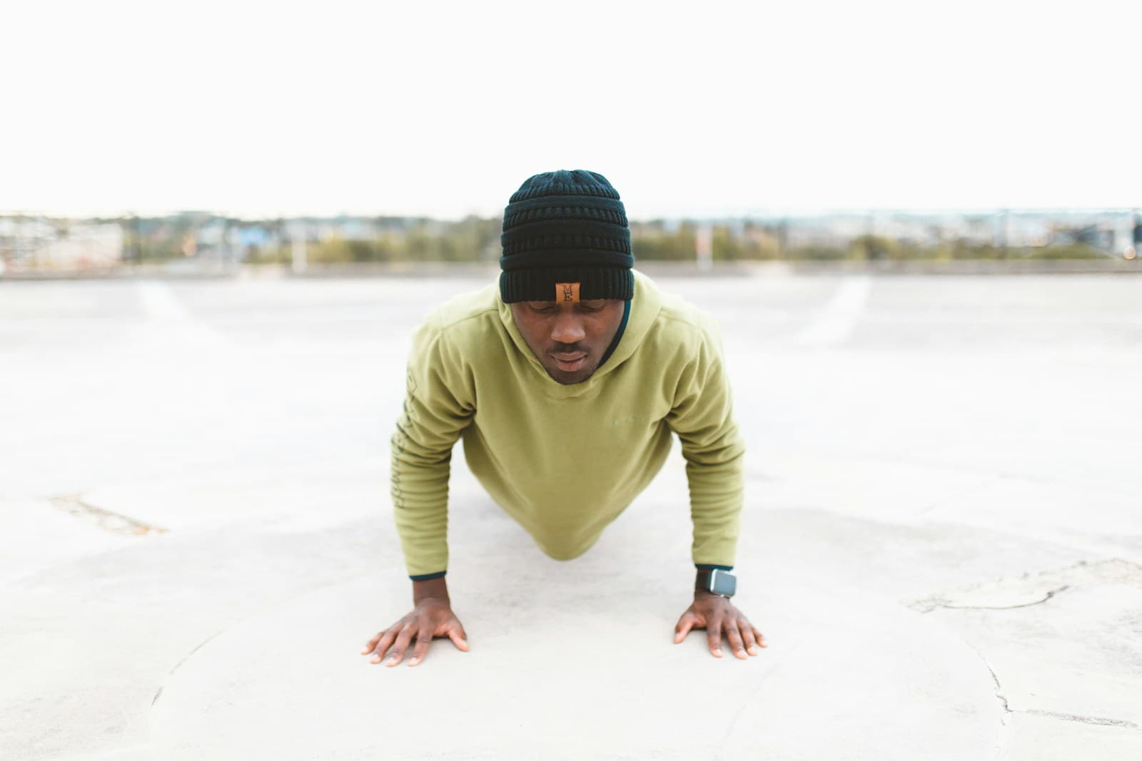 Man at the top of a push-up on a concrete surface, arms locked out, body in a straight line