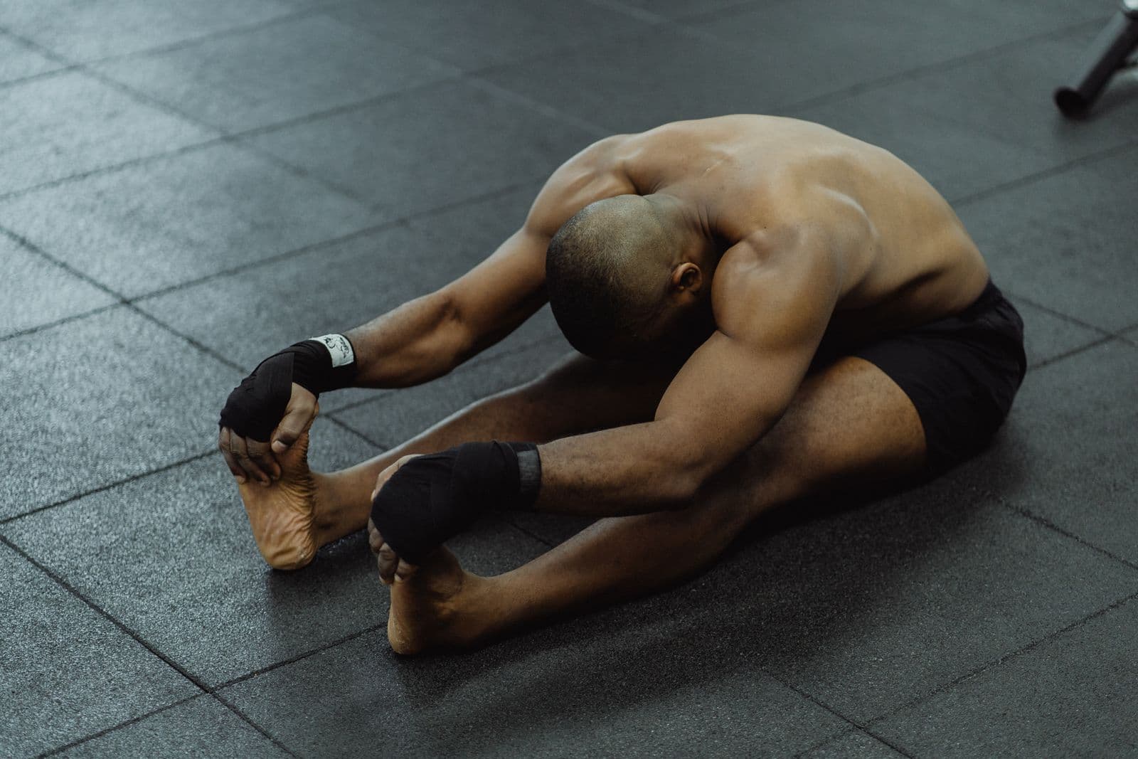 Person seated on the floor folded forward, spine rounding through a full toe-touch stretch
