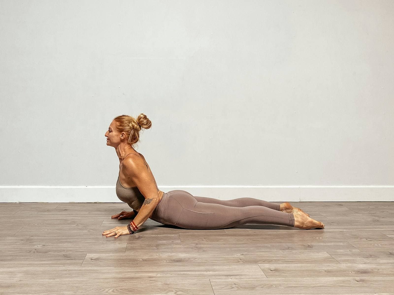 Woman in cobra pose demonstrating thoracic spine extension on a hardwood floor