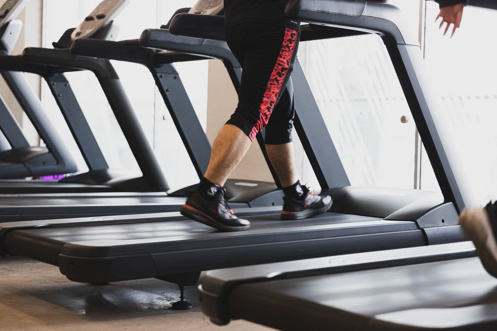 Person walking at a steady pace on a treadmill in a bright gym