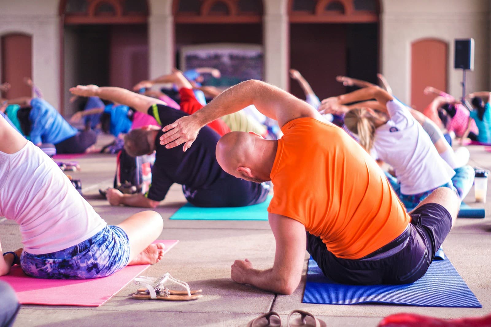 Group exercise class doing seated side bends together on yoga mats