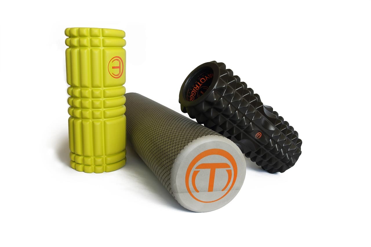 Three foam rollers of different colors and textures arranged on a white background