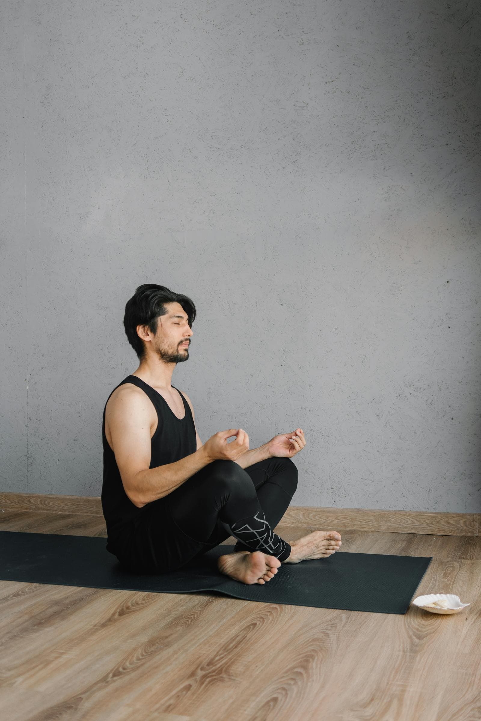 Man sitting cross-legged on a yoga mat practicing seated breathing