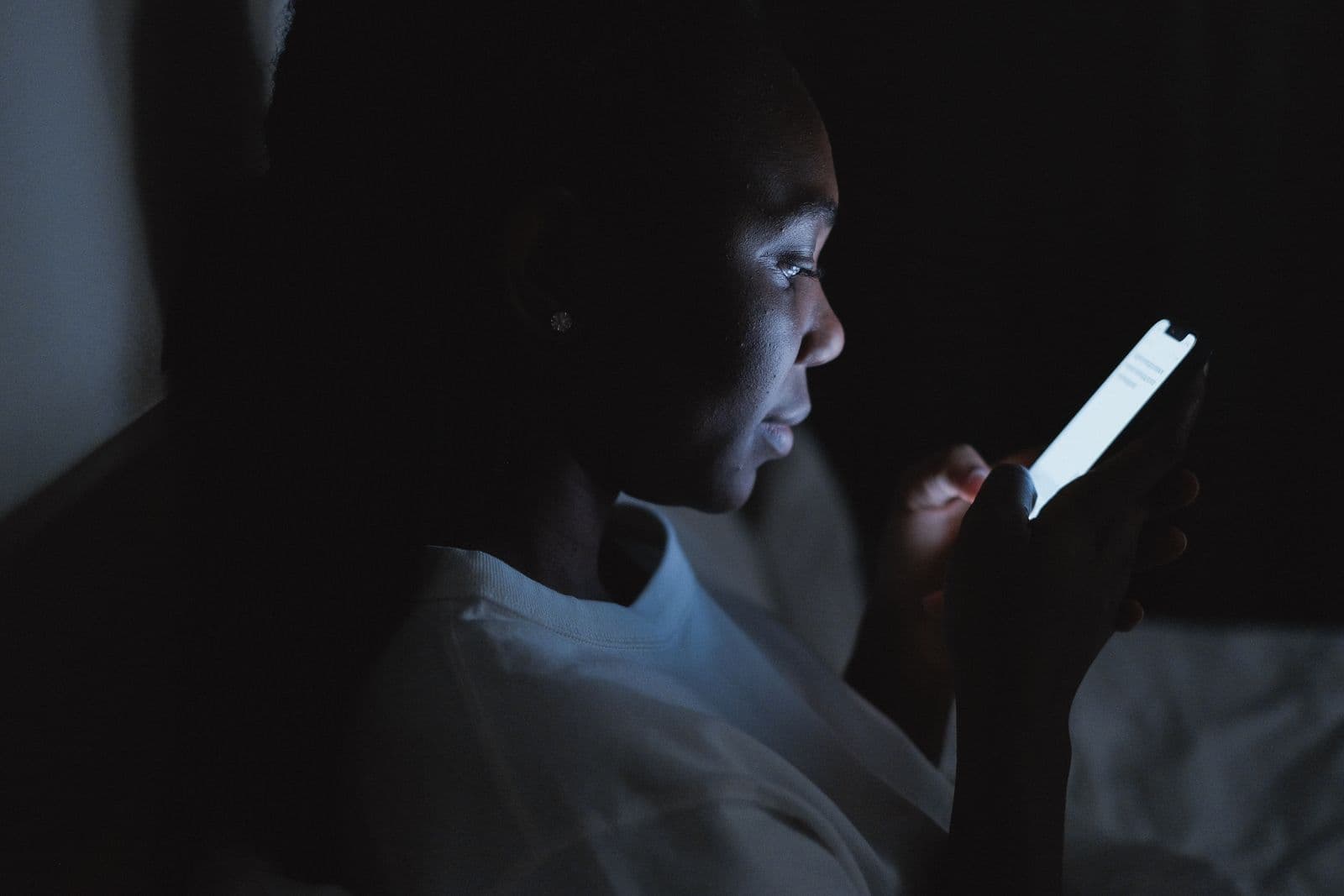 Person looking at a lit phone screen in a dark bedroom